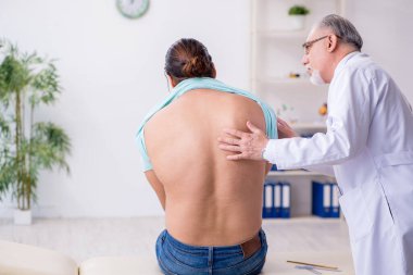 Genç sırtı yaralı adam deneyimli erkek doktoru ziyaret ediyor.