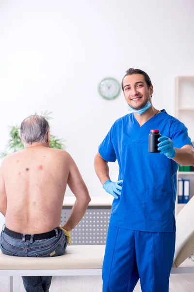 Homem velho visitando jovem médico dermatologista masculino — Fotografia de Stock