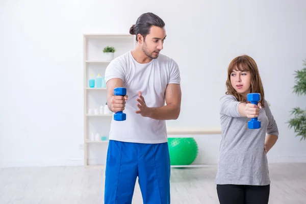 Jovem fazendo exercícios esportivos com treinador pessoal — Fotografia de Stock