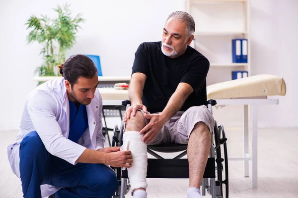 Old injured man visiting young male doctor traumatologist — Stock Photo, Image