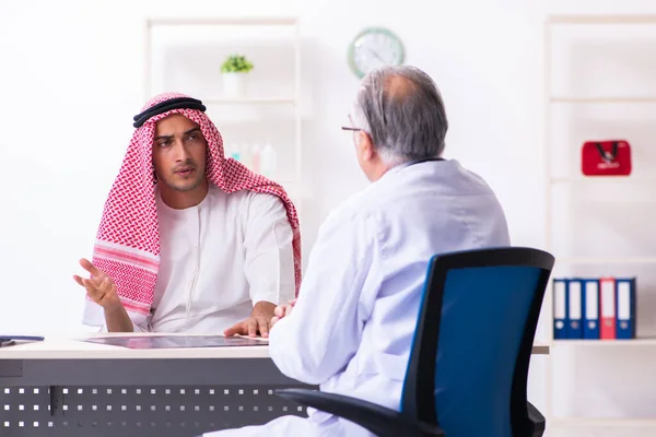 Young male arab visiting experienced male doctor — Stock fotografie