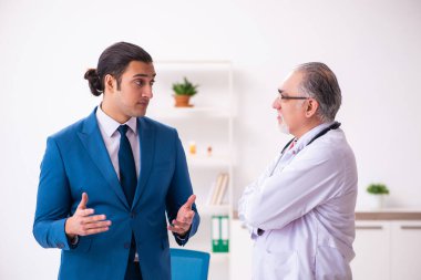 Genç işadamı yaşlı doktorla görüşüyor.