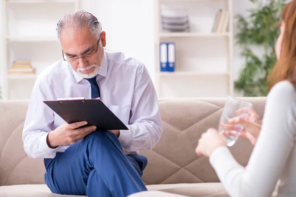 Junge Frau besucht alten Arzt-Psychologen — Stockfoto