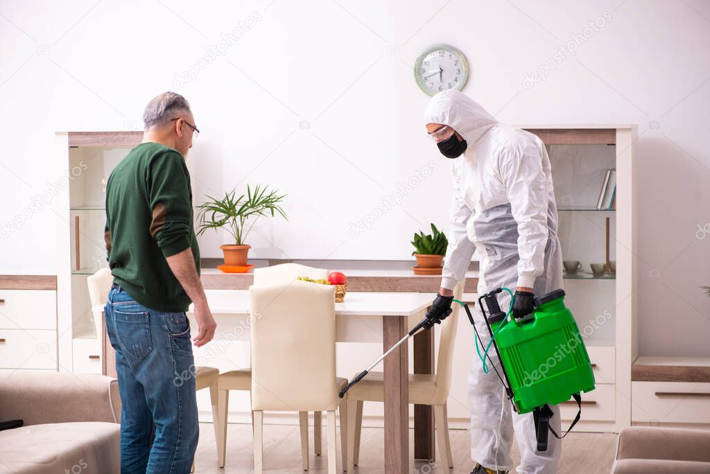 Young male sanitizer and old man indoors