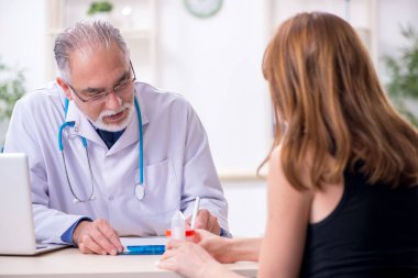 Genç kadın yaşlı erkek doktoru ziyaret ediyor.