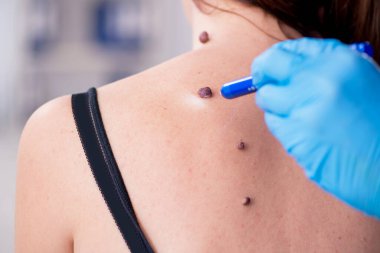 Genç bir kadın erkek doktor dermatoloğunu ziyaret ediyor.