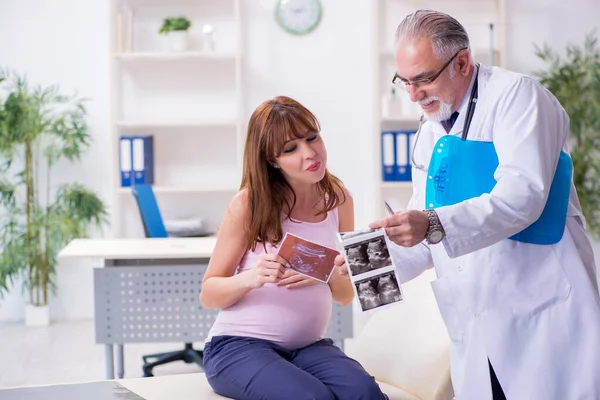 Giovane donna incinta visita vecchio medico ginecologo maschile — Foto Stock