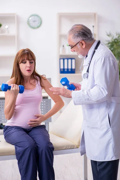 Ung gravid kvinna besöker gammal manlig läkare gynekolog — Stockfoto