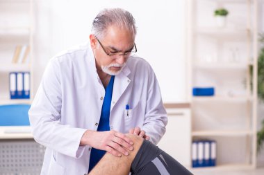 Genç erkek hasta yaşlı doktor travmatoloğu ziyaret ediyor.