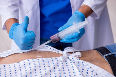 Yaşlı adam genç erkek stajyer doktoru ziyaret ediyor.