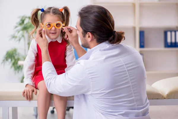 Menina pequena visitando jovem médico oculista masculino — Fotografia de Stock