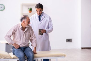 Yaşlı hasta genç erkek doktoru ziyaret ediyor.