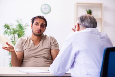 Yaralı genç adam deneyimli erkek doktor travmasını ziyaret ediyor.