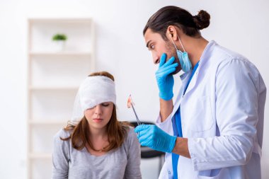 Genç baş yaralı kadın genç erkek doktoru ziyaret ediyor.