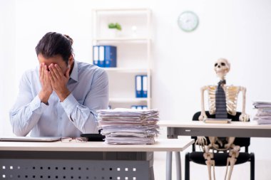 Genç erkek çalışan ve iskelet ofiste.