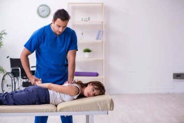 Yaralı kadın genç erkek doktor osteopat 'ı ziyaret ediyor.