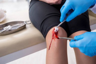 Erkek doktoru ziyaret eden bacağı yaralı bir kadın.