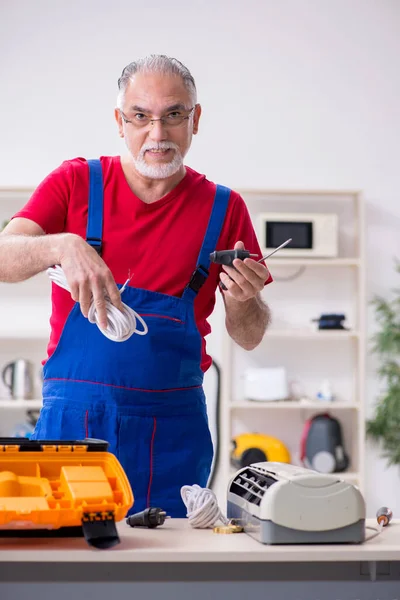 Viejo contratista reparando aire acondicionado en interiores —  Fotos de Stock