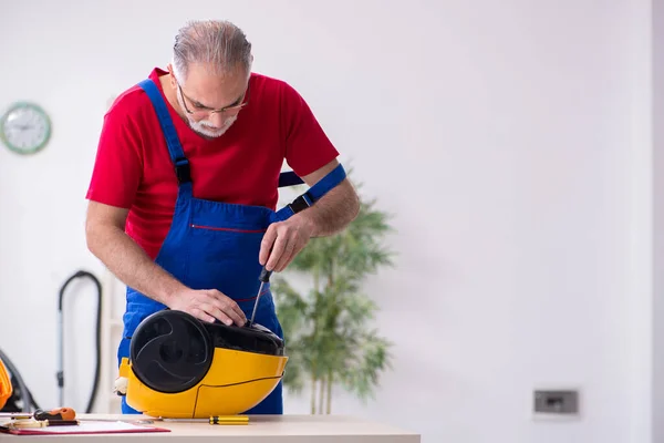 Evde elektrik süpürgesi tamir eden yaşlı bir erkek müteahhit. — Stok fotoğraf