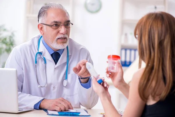 Jovem mulher visitando velho médico masculino — Fotografia de Stock