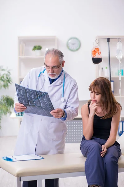 Jonge vrouw bezoekt oude mannelijke arts — Stockfoto