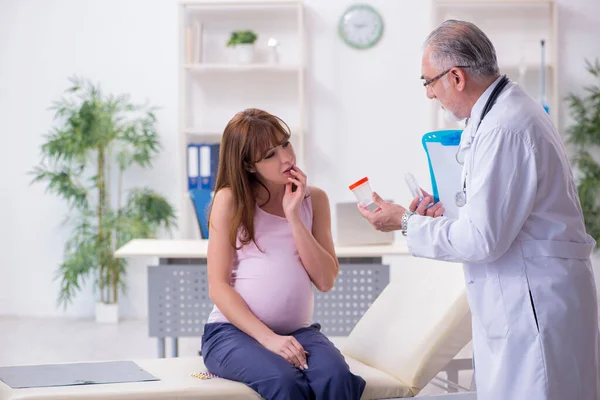 Young pregnant woman visiting old male doctor gynecologist — Stock Photo, Image