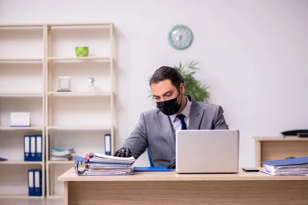 Jovem funcionário do sexo masculino no escritório durante a doença pandêmica — Fotografia de Stock