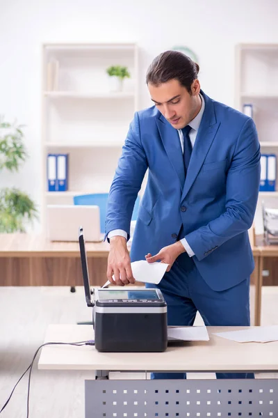 Young male employee making copies at copying machine — Stock Photo, Image