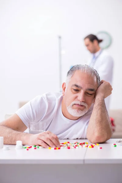 Genç erkek doktor yaşlı erkek hastayı ziyaret ediyor. — Stok fotoğraf