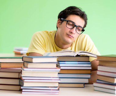 Sınavdan önce okumak için çok fazla kitabı olan öğrenci