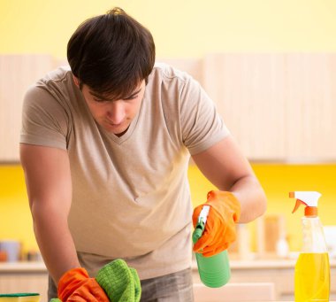 Bekar adam mutfağı temizliyor.