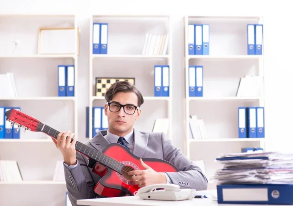 Joven hombre de negocios guapo tocando la guitarra en la oficina — Foto de Stock