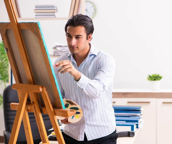 Jovem e bonito funcionário desfrutando de pintura no escritório — Fotografia de Stock