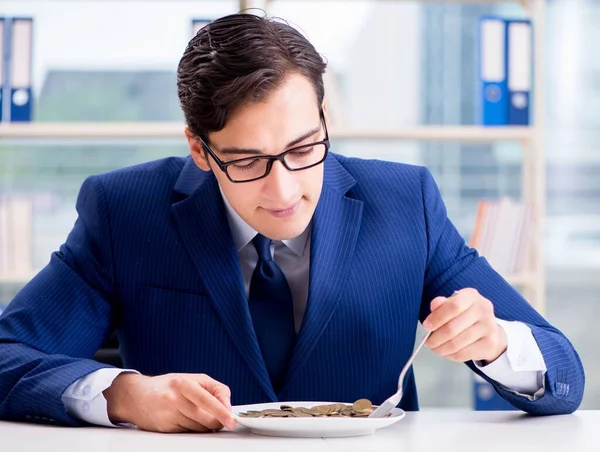 Funny businessman eating gold coins in office