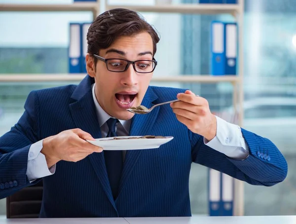 Divertido hombre de negocios comiendo monedas de oro en la oficina — Foto de Stock