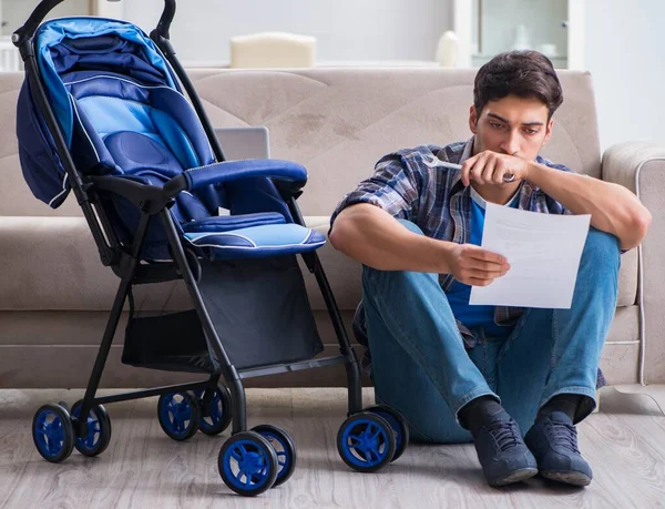 Jovem pai montando carrinho de bebê em casa — Fotografia de Stock