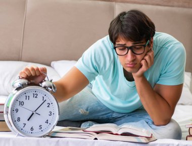 Sınavlara hazırlanan öğrenci yatak odasında oturuyor.