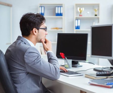 Birçok ekranın önünde oturan bir iş adamı
