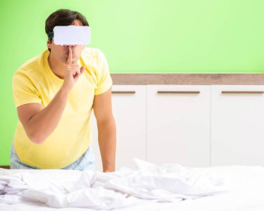 Yatak odasında sanal gözlüklü genç adam.