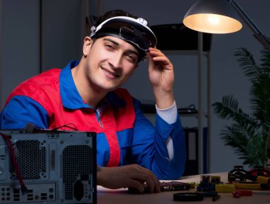 Bilgisayar uzmanı gece geç saatlerde bilgisayarı tamir ediyor.