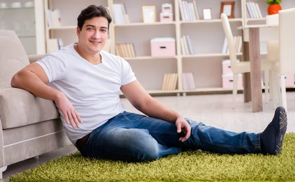 Jovem homem bonito feliz no chão do tapete — Fotografia de Stock