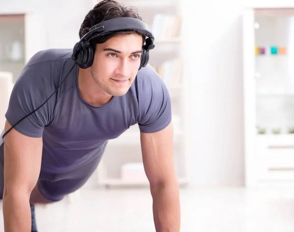 Мужчина занимается спортом дома и слушает музыку — стоковое фото
