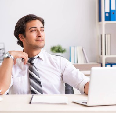 Genç yakışıklı işadamı ofiste çalışıyor.