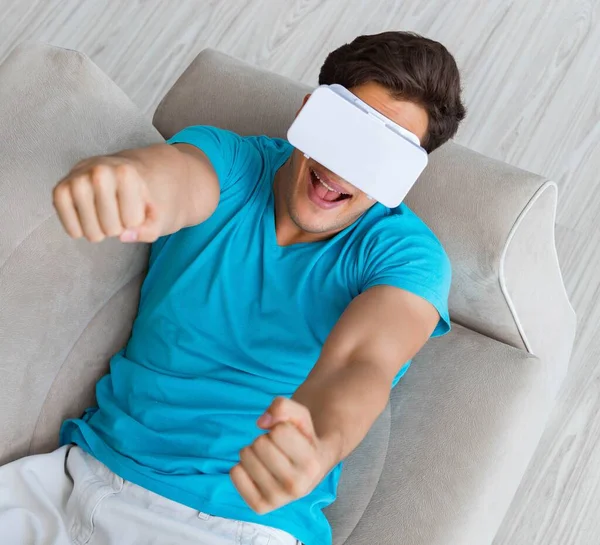 Jovem vestindo óculos VR relaxando no sofá sofá — Fotografia de Stock