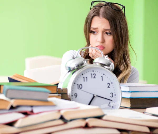 Jonge vrouwelijke student bereidt zich voor op examens met veel boeken in de tijd — Stockfoto
