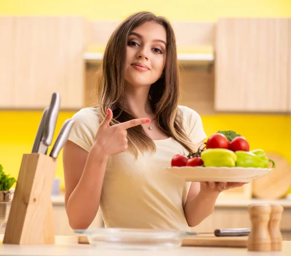 Young woman preparing salad at home in kitchen — Stock Photo, Image