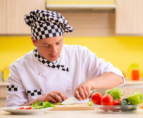 Joven cocinero profesional preparando ensalada en la cocina — Foto de Stock