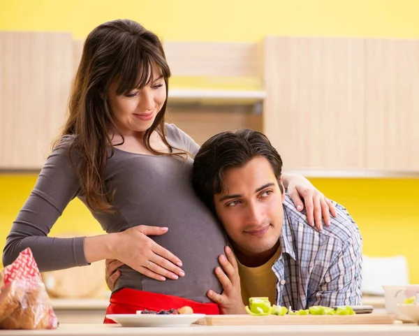 Man and pregnant woman preparing salad in kitchen — Stock Photo, Image