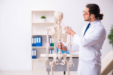 İskeleti olan genç erkek doktor.