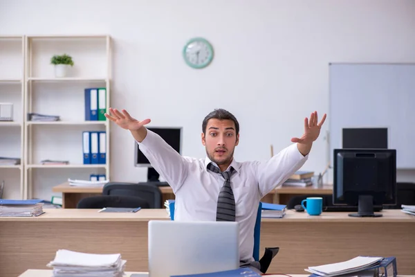 Joven empleado masculino infeliz con el trabajo excesivo —  Fotos de Stock